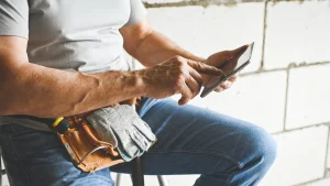 A tradesperson using a tablet for marketing while wearing a tool belt on a construction site.